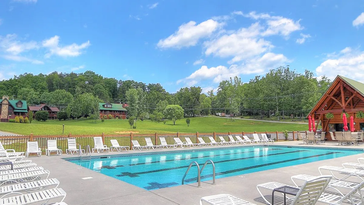The image features a vibrant outdoor swimming pool with lounge chairs, a landscaped lawn, and an outdoor pavilion. The atmosphere is fun and inviting, perfect for family gatherings and relaxation. The bright, sunny setting is ideal for days spent splashing in the pool and enjoying snacks under the pavilion.
