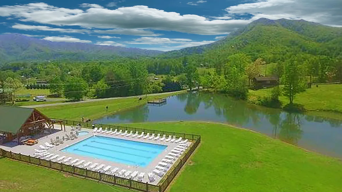A lively yet serene glimpse of a resort swimming pool bordered by lush greenery and mountains in the background. The calm water reflects the sky, with space for swimming, sunbathing, and family relaxation, capturing the resort perk mentioned in the content.