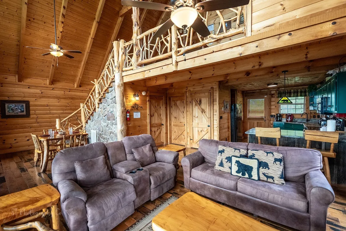 This image centers on a rustic dining table paired with wooden beams and a stone wall, evoking warmth and a sense of togetherness. Comfortable sofas in the background make the dining area feel like the heart of the home, ideal for shared meals and lively conversation.
