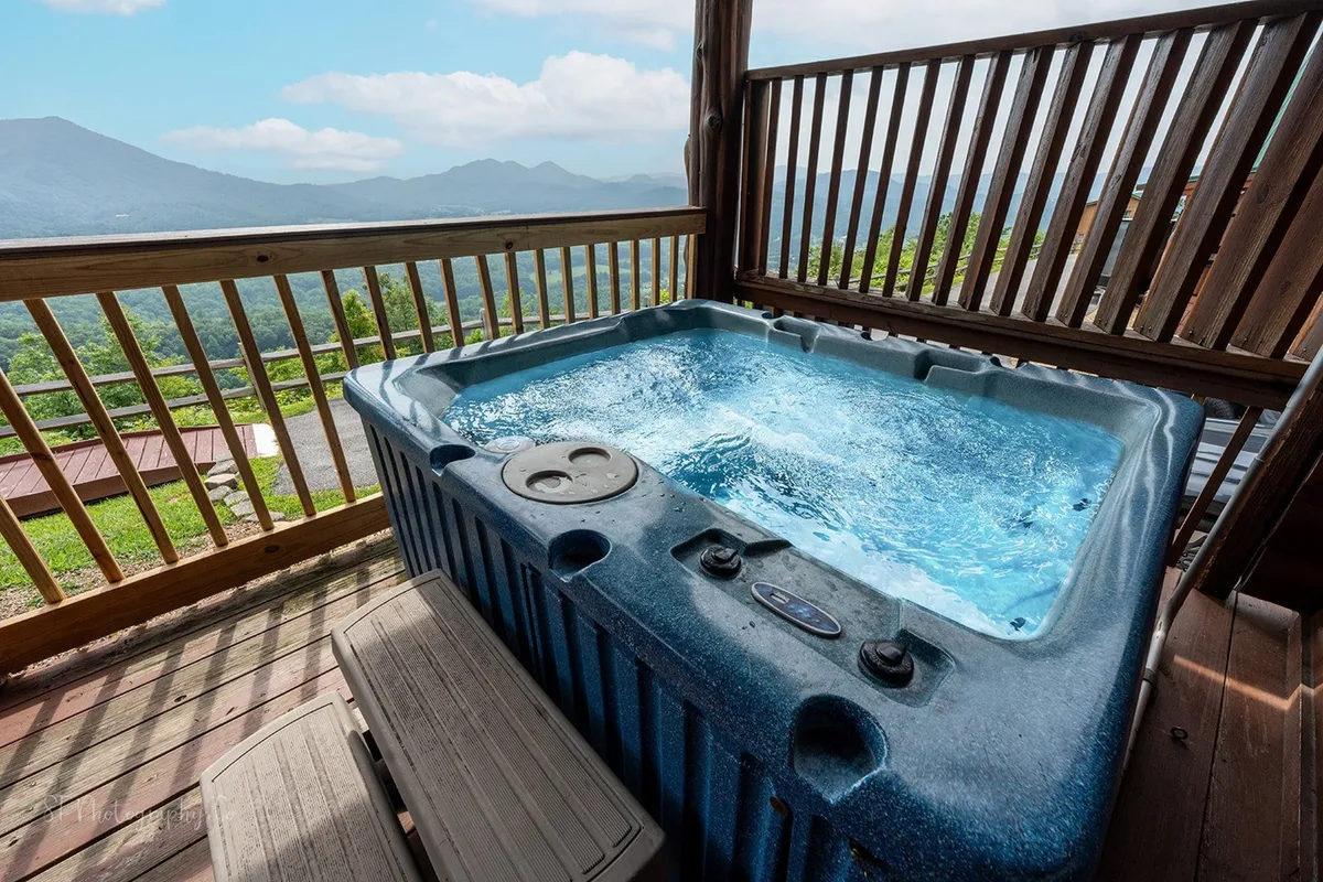 This exterior shot captures a bubbling hot tub on a wooden deck with a clear view of the mountains beyond. The tranquil setting is perfect for sunset soaks, stargazing, or socializing with friends after a day of exploring local attractions.